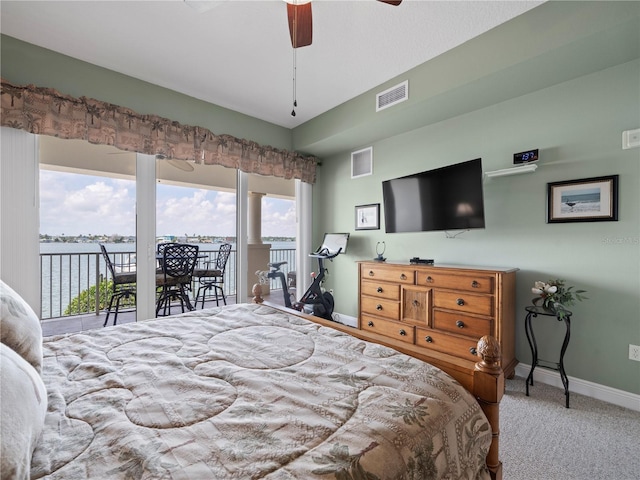 carpeted bedroom with access to exterior, visible vents, a water view, and baseboards