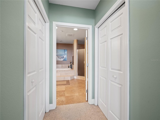 hall featuring light colored carpet and visible vents