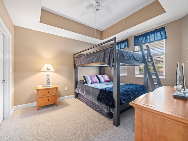 bedroom with light carpet, baseboards, and a tray ceiling