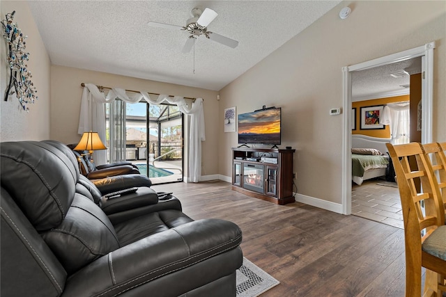 living room featuring lofted ceiling, ceiling fan, a textured ceiling, wood finished floors, and baseboards