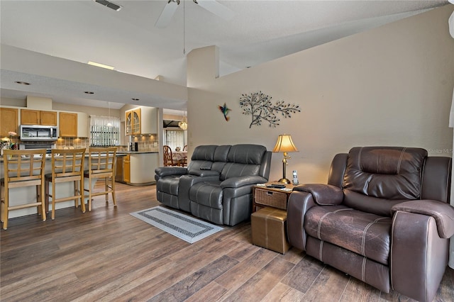 living area featuring lofted ceiling, dark wood finished floors, and a ceiling fan