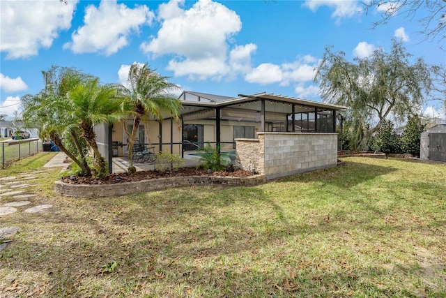 back of house featuring glass enclosure and a yard