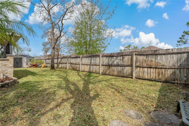 view of yard featuring a fenced backyard, an outdoor structure, and a storage unit