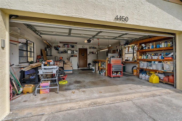 garage featuring freestanding refrigerator, a workshop area, and a garage door opener