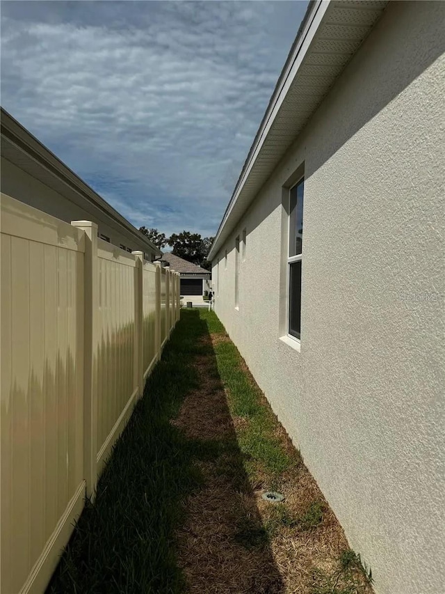 view of side of property featuring fence and stucco siding