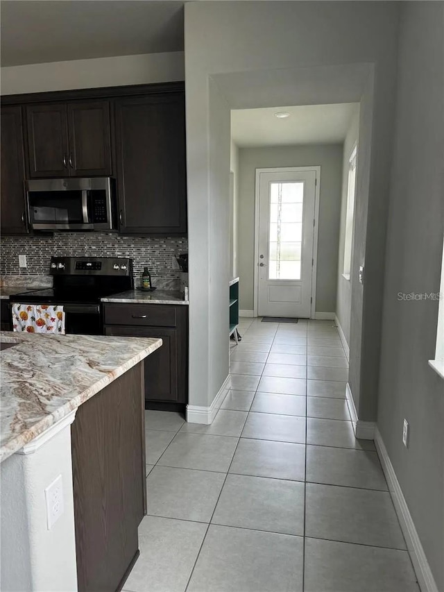 kitchen with light tile patterned floors, tasteful backsplash, stainless steel microwave, dark brown cabinetry, and black range with electric cooktop