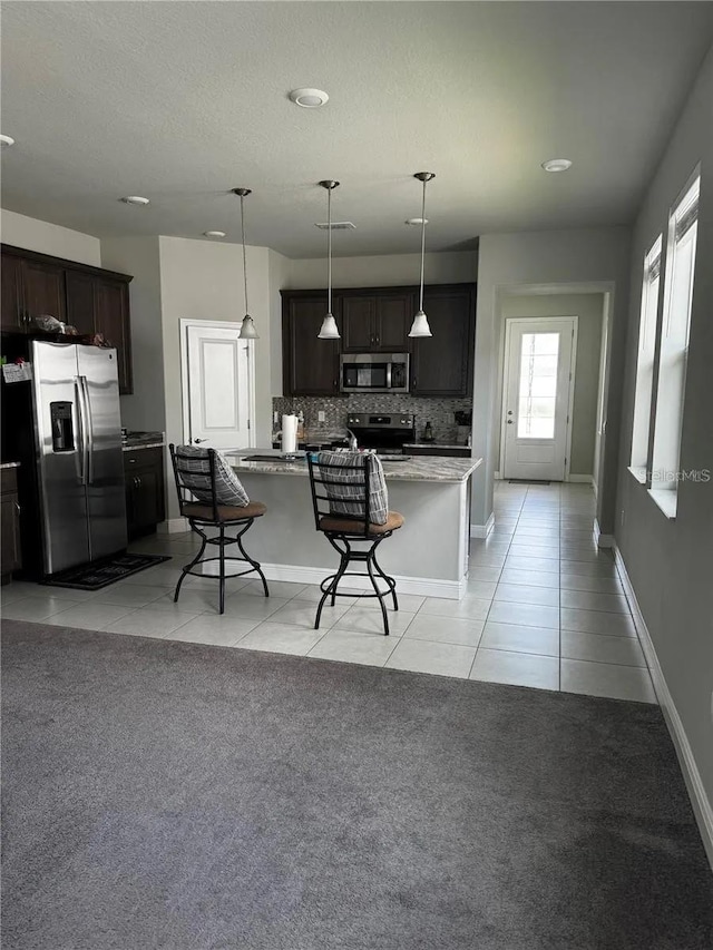 kitchen featuring light tile patterned floors, stainless steel appliances, decorative light fixtures, and dark brown cabinetry