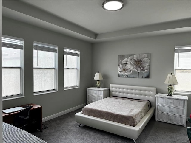 bedroom featuring multiple windows, dark carpet, and baseboards