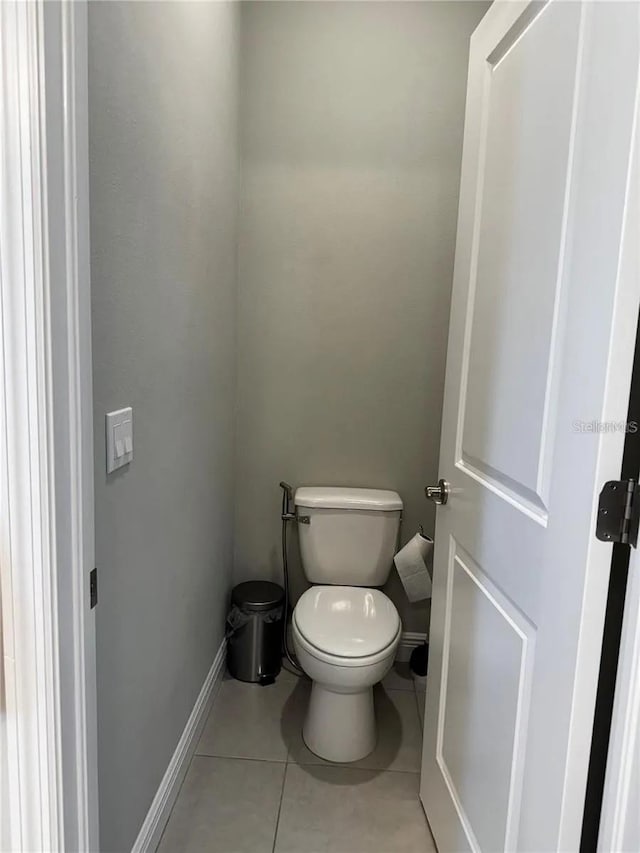 bathroom with toilet, tile patterned flooring, and baseboards