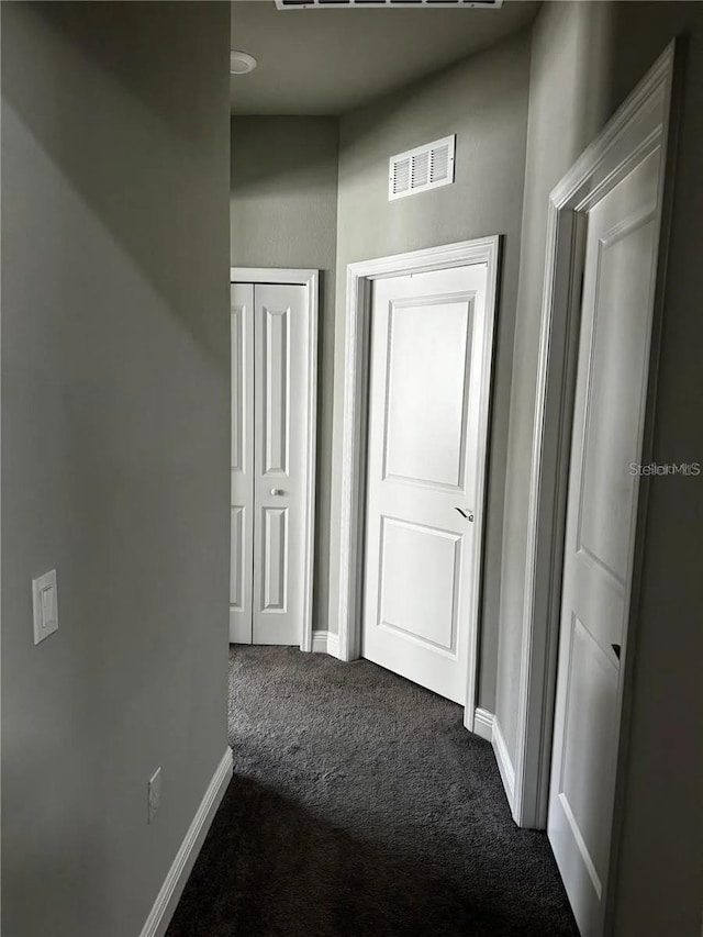 corridor featuring carpet floors, visible vents, and baseboards