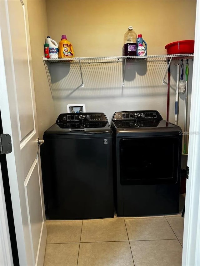 clothes washing area featuring washing machine and dryer, laundry area, and light tile patterned floors