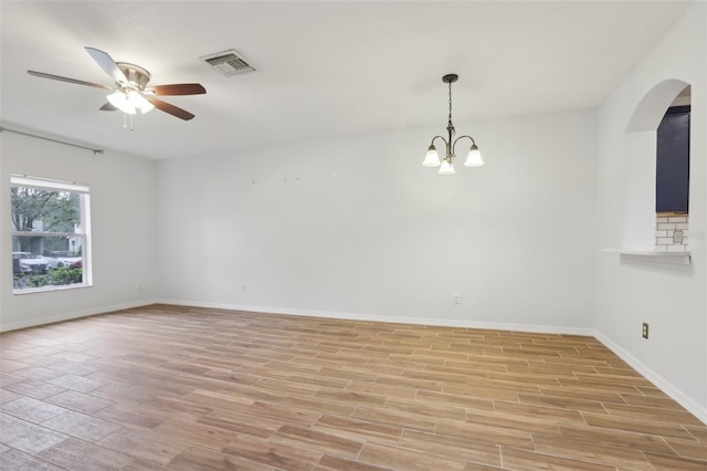 empty room featuring light wood-style floors, baseboards, visible vents, and ceiling fan with notable chandelier