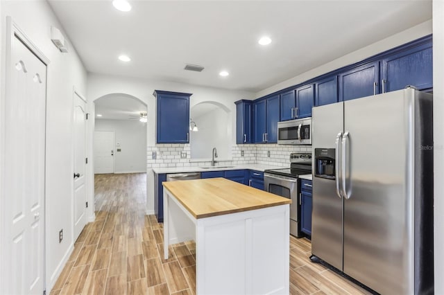 kitchen with stainless steel appliances, blue cabinetry, a sink, and a center island