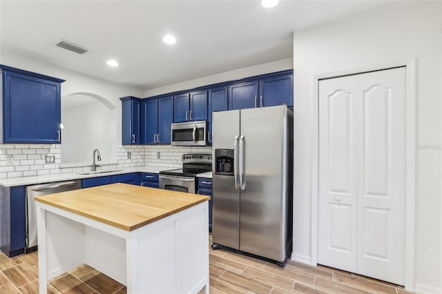 kitchen featuring stainless steel appliances, a center island, a sink, and blue cabinetry