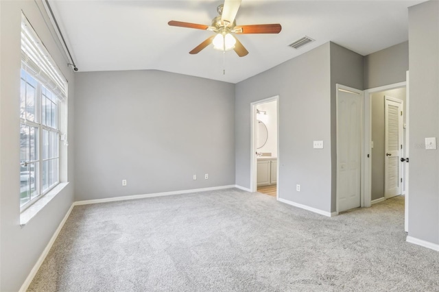 unfurnished bedroom featuring light carpet, baseboards, visible vents, and ensuite bathroom