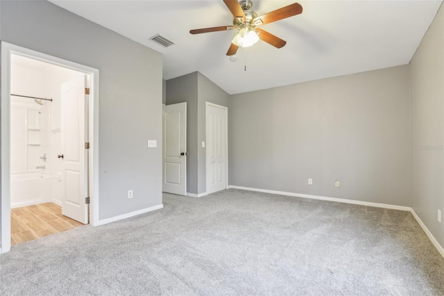 unfurnished bedroom featuring baseboards, visible vents, ensuite bathroom, and light colored carpet