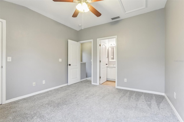 unfurnished bedroom with light colored carpet, visible vents, ensuite bathroom, attic access, and baseboards