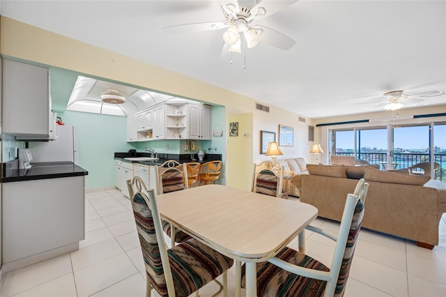 dining room featuring a city view, light tile patterned flooring, visible vents, and a ceiling fan