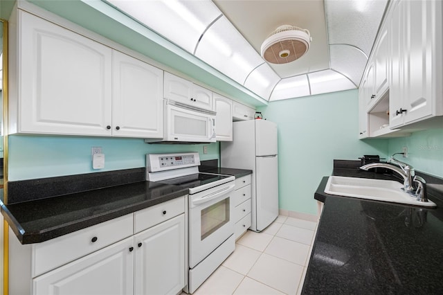 kitchen with white appliances, white cabinetry, a sink, and light tile patterned flooring