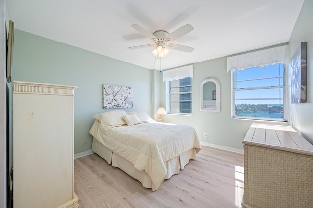 bedroom with light wood-style flooring, multiple windows, and baseboards