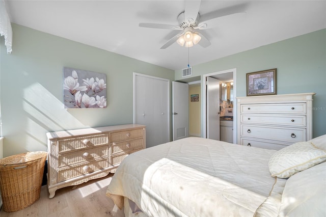 bedroom featuring a closet, wood finished floors, visible vents, and connected bathroom