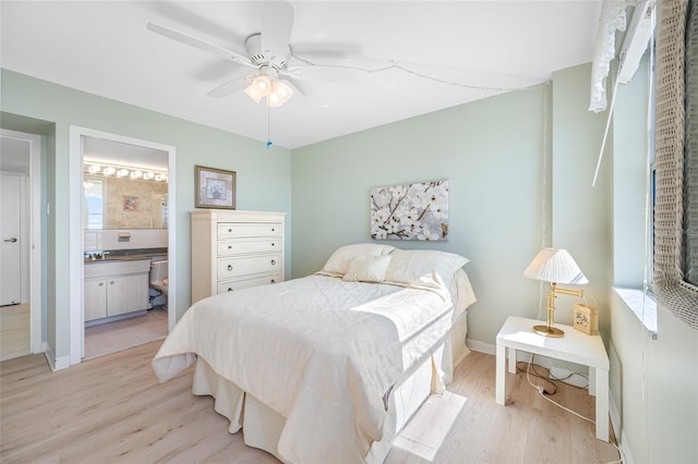 bedroom with multiple windows, light wood-type flooring, and ensuite bath