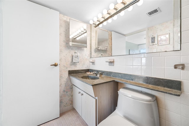 bathroom with visible vents, decorative backsplash, toilet, vanity, and tile walls