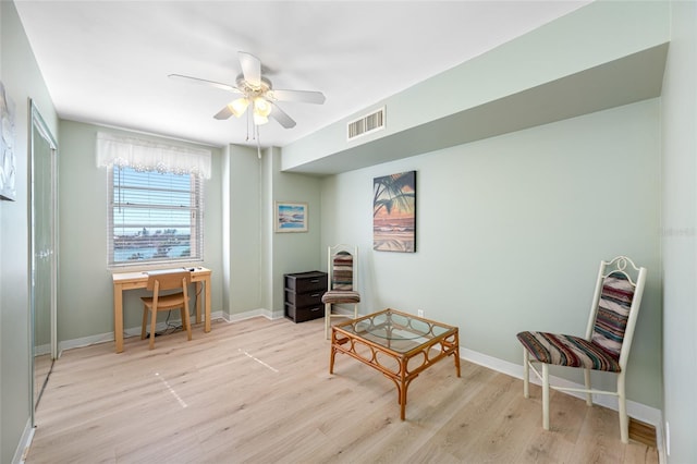 sitting room featuring a ceiling fan, visible vents, baseboards, and wood finished floors