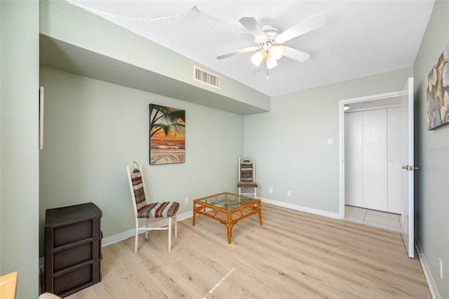 sitting room featuring a ceiling fan, light wood-style flooring, visible vents, and baseboards