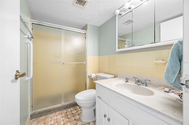 bathroom featuring a textured ceiling, toilet, visible vents, tile walls, and a shower stall