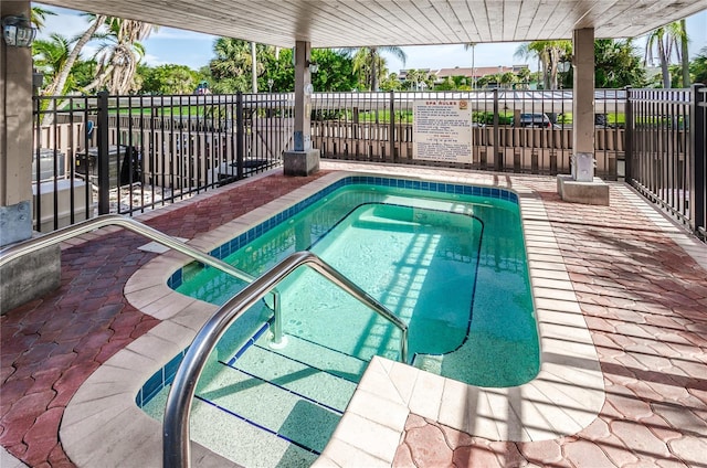 view of swimming pool with a community hot tub and fence