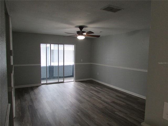 spare room featuring dark wood-style flooring, visible vents, ceiling fan, and baseboards