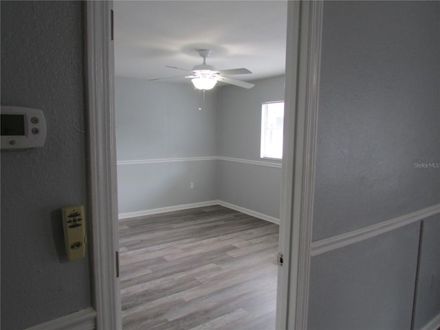 empty room with light wood finished floors, ceiling fan, and baseboards