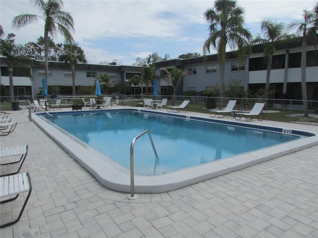 community pool with a patio and fence