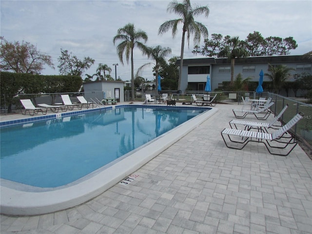 community pool with a patio and fence