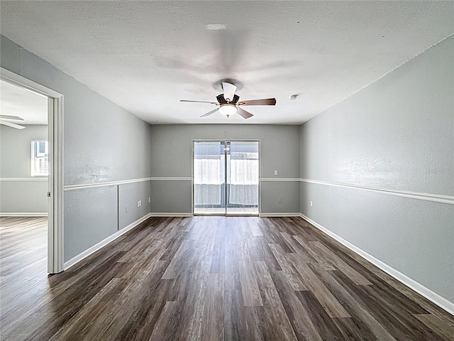 spare room with baseboards, dark wood-style flooring, and a ceiling fan