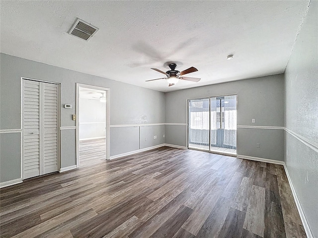 spare room featuring wood finished floors, a ceiling fan, visible vents, and a textured ceiling