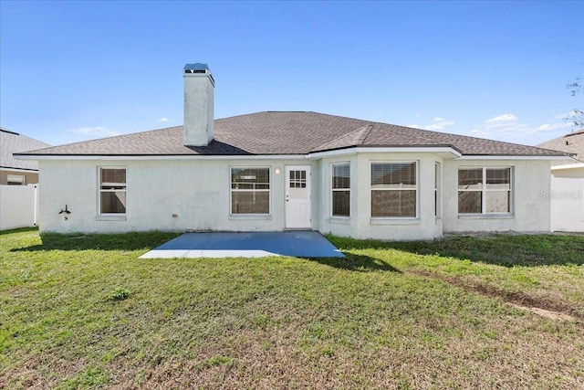 rear view of property featuring a chimney, a lawn, a patio area, and fence