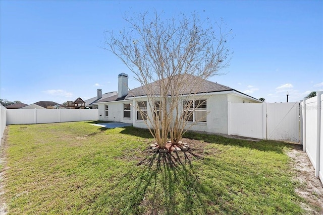 back of property featuring a gate, a fenced backyard, and a yard