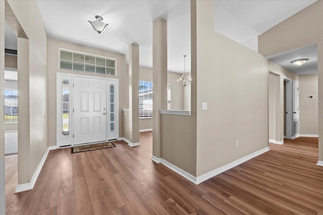 foyer entrance featuring an inviting chandelier, wood finished floors, and baseboards