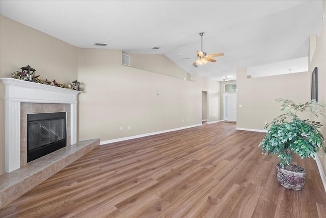 unfurnished living room with light wood-type flooring, lofted ceiling, visible vents, and a tile fireplace