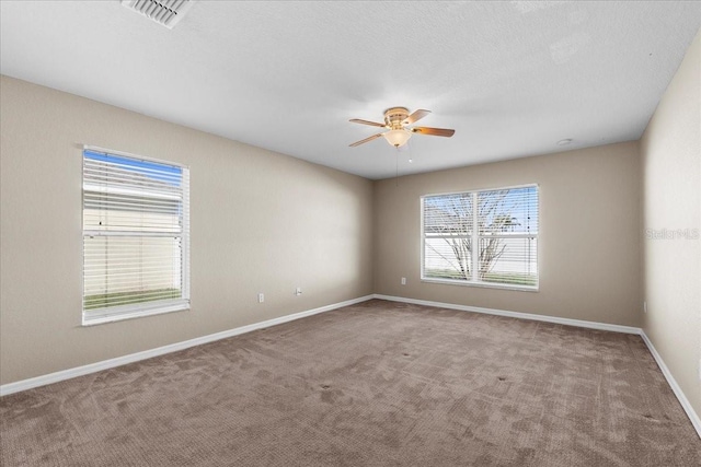 spare room featuring a textured ceiling, carpet flooring, a ceiling fan, visible vents, and baseboards