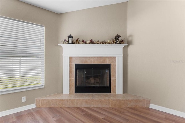 interior details with baseboards, wood finished floors, and a tile fireplace