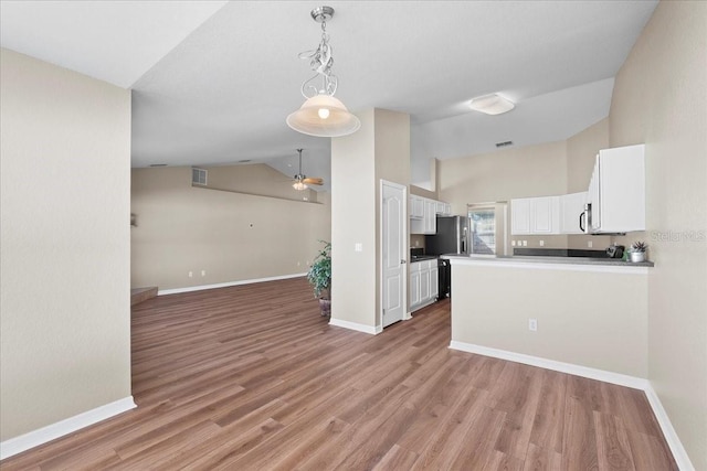 kitchen featuring white cabinets, vaulted ceiling, baseboards, and open floor plan