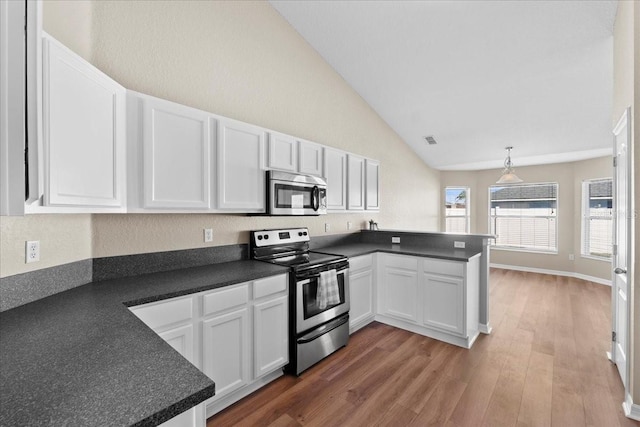 kitchen with a peninsula, dark countertops, white cabinets, and stainless steel appliances