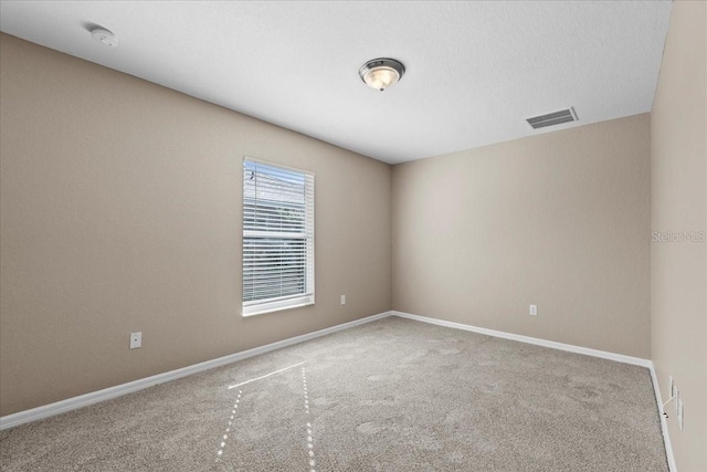 spare room with carpet, visible vents, and baseboards