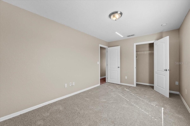 unfurnished bedroom with a closet, carpet, visible vents, and baseboards