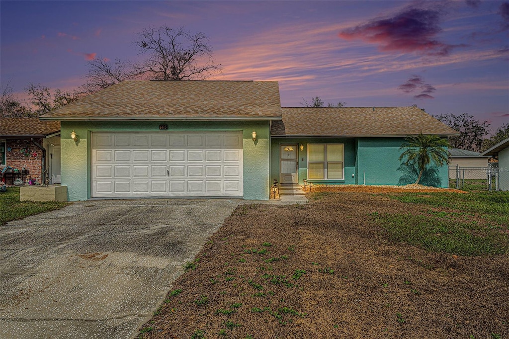 view of front of property with a garage, concrete driveway, a lawn, and stucco siding