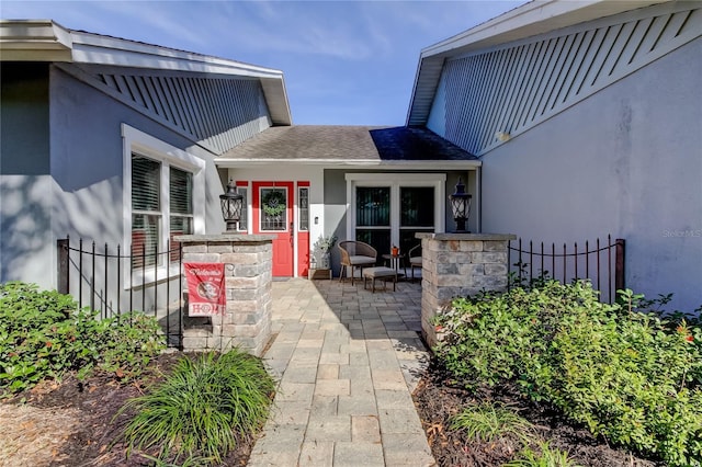 doorway to property featuring roof with shingles and stucco siding