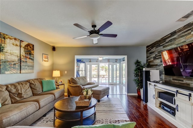 living room with baseboards, visible vents, a ceiling fan, dark wood-style flooring, and a textured ceiling